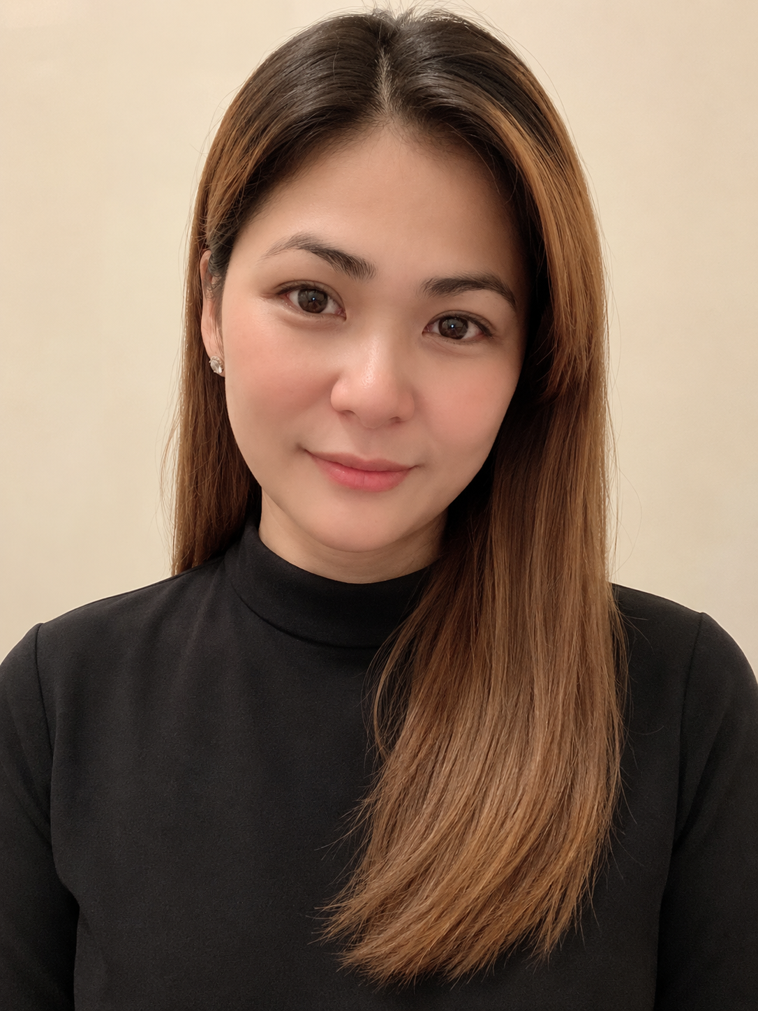 Professional portrait of Toni Perlas-Karagöz in a black top against a warm neutral background